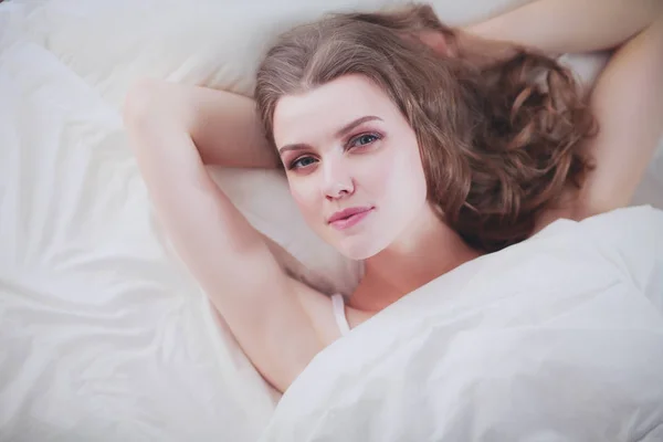 Pretty woman lying down on her bed at home. — Stock Photo, Image