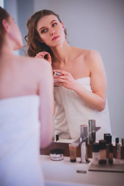 Giovane donna che si guarda allo specchio e si trucca. — Foto Stock