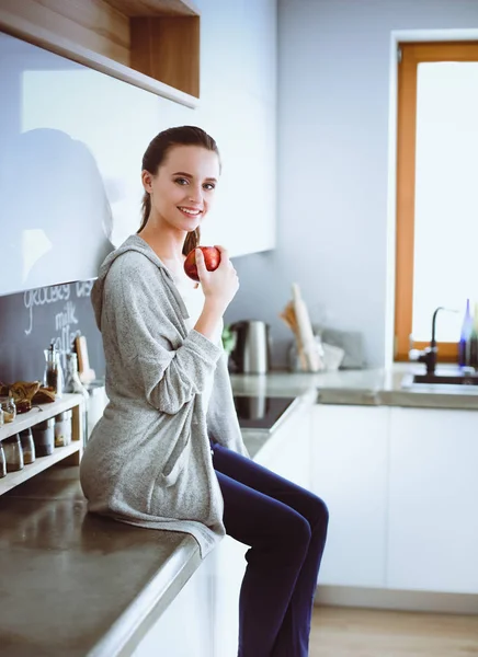 Mujer usando el teléfono móvil sentado en la cocina moderna . —  Fotos de Stock
