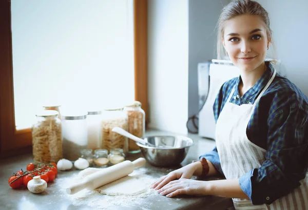 Beautiful woman cooking cake in kitchen standing near desk. — Stock Photo, Image