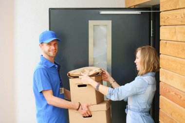 Mavi üniformalı gülümseyen kurye servis konseptine paket kutusu teslim eden teslimatçı. Mavi üniformalı gülümseyen teslimatçı.