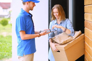 Mavi üniformalı gülümseyen kurye servis konseptine paket kutusu teslim eden teslimatçı. Mavi üniformalı gülümseyen teslimatçı.