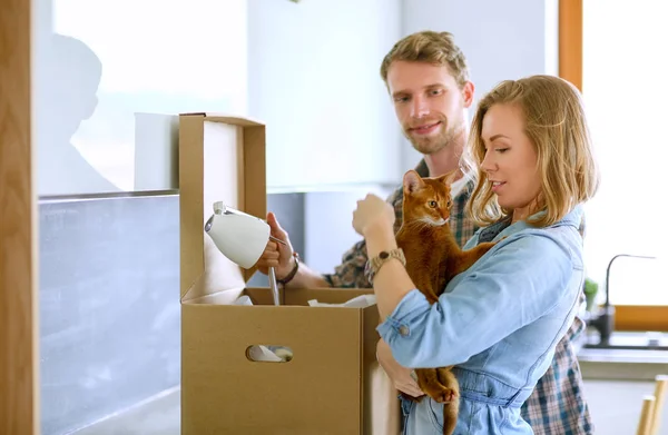 Casal jovem carregando grande caixa de papelão em casa nova. Casal jovem — Fotografia de Stock