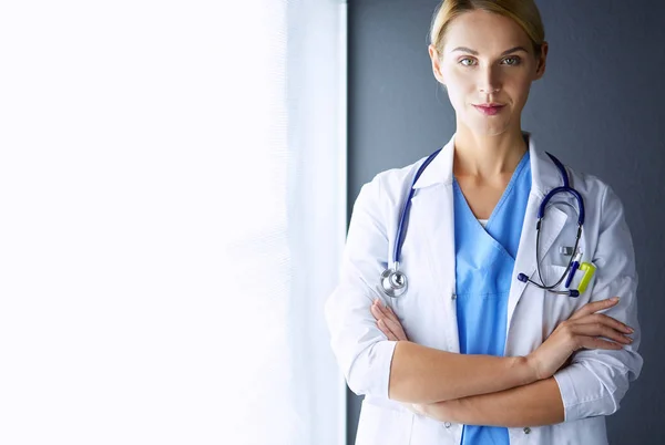 Retrato de una joven doctora con una bata blanca de pie en el hospital. —  Fotos de Stock