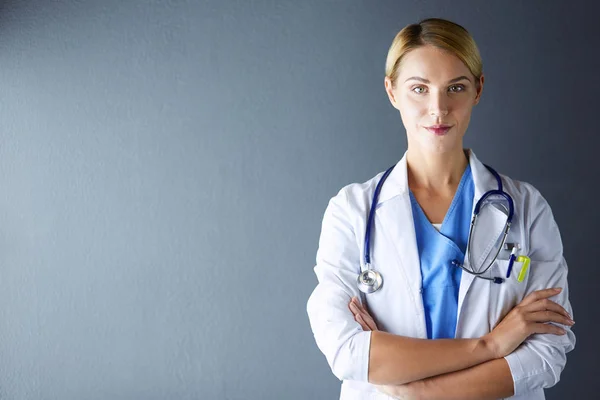 Retrato de una joven doctora con una bata blanca de pie en el hospital. — Foto de Stock