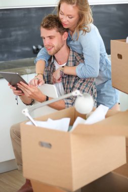 Genç bir çift yeni ev içinde hareket. Oturma ve açma sonra rahatlatıcı. Bir şey üstünde laptop arıyorum. Genç Çift