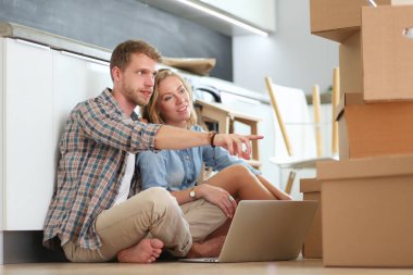 Genç bir çift yeni ev içinde hareket. Oturma ve açma sonra rahatlatıcı. Bir şey üstünde laptop arıyorum. Genç Çift