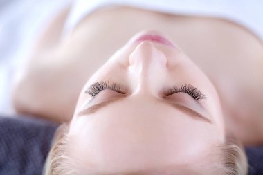 Masaj masasında uzanmış gözleri kapalı rahatlayan genç bir kadın. - Kadın. Spa salonu