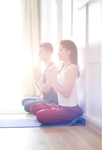 Joven pareja sana en posición de yoga sobre fondo blanco — Foto de Stock