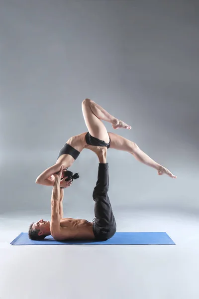 Jeune couple pratiquant l'acro yoga sur tapis en studio ensemble. Acroyoga. Du yoga. Yoga partenaire . — Photo