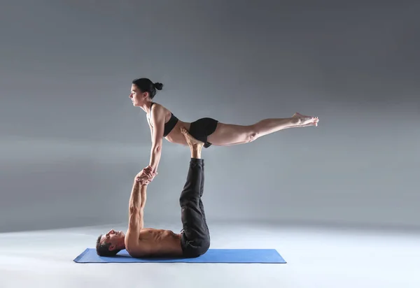 Young couple practicing acro yoga on mat in studio together. Acroyoga. Couple yoga. Partner yoga.