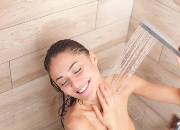 Young beautyful woman under shower in bathroom. Stock Photo