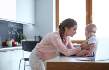 Annesi bebeğini evde parlak mutfakta ile.
