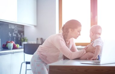 Annesi bebeğini evde parlak mutfakta ile.
