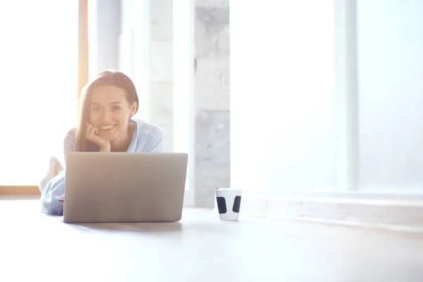 Giovane bella donna a casa seduta sul pavimento con il computer portatile. Giovane bella donna . — Foto Stock