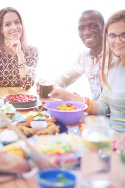 Ahşap masada otururken birlikte yemek yiyen bir grup insanın üst düzey görüntüsü. Masada yemek var. İnsanlar fast food yiyor..