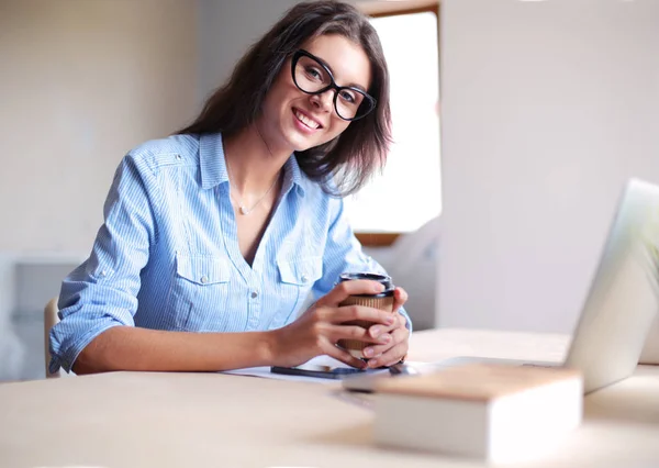 Jovem mulher sentada na mesa do escritório, olhando para a tela do computador portátil. Jovem mulher — Fotografia de Stock