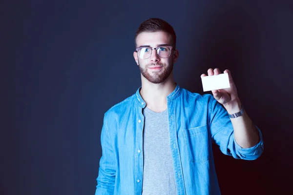 Joven sosteniendo una tarjeta de crédito de pie sobre fondo gris. Joven empresario. —  Fotos de Stock