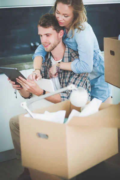 Young couple moving in new home.Sitting and relaxing after unpacking.Looking something on laptop. Young couple — Stock Photo, Image