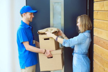 Mavi üniformalı gülümseyen kurye servis konseptine paket kutusu teslim eden teslimatçı. Mavi üniformalı gülümseyen teslimatçı.