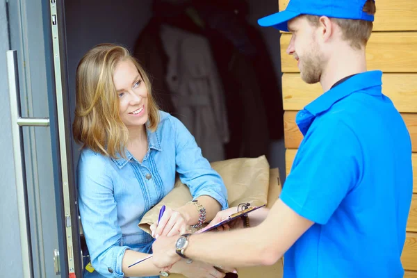 Repartidor sonriente con uniforme azul que entrega la caja de paquetes al destinatario: concepto de servicio de mensajería. Repartidor sonriente en uniforme azul — Foto de Stock