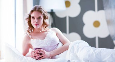 Genç kadın yatakta yatan ise kahve veya çay içme