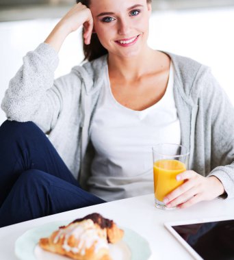 Mutfakta portakal suyu ve tableti olan genç bir kadın..