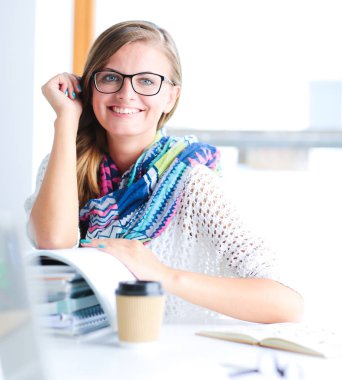 Kitapların arasında bir masada oturan genç bir kadın. Öğrenci