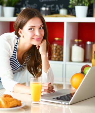 Genç bayan mutfakta masanın yanında oturuyor.