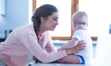 Annesi bebeğini evde parlak mutfakta ile.