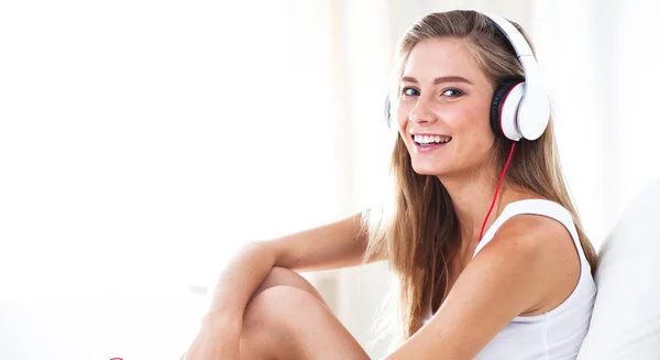 Portrait de belle femme le matin écoutant de la musique assise sur le lit à la maison — Photo