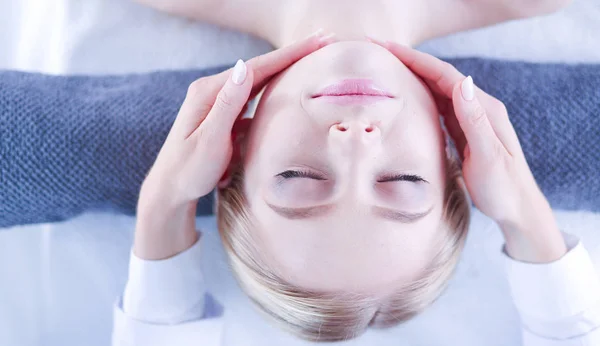 Mujer joven acostada en una mesa de masaje, relajándose con los ojos cerrados . — Foto de Stock