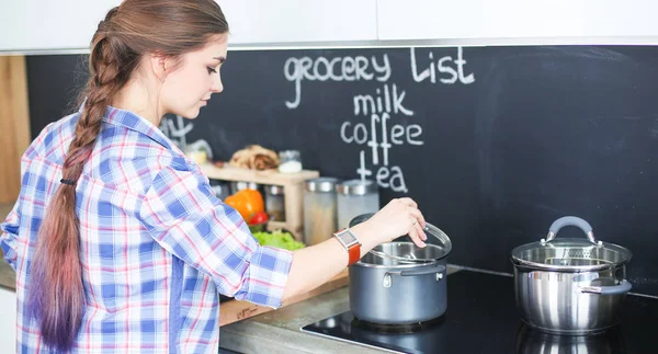 Mutfakta sobanın yanında duran genç bir kadın. .