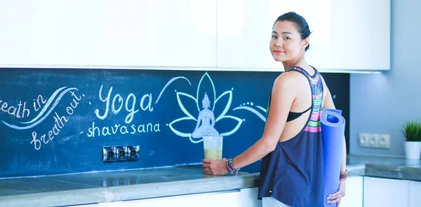 Retrato de una mujer sonriente sosteniendo en su mano una esterilla de yoga mientras estaba de pie en el estudio. Yoga. Una mujer. Bienestar — Foto de Stock