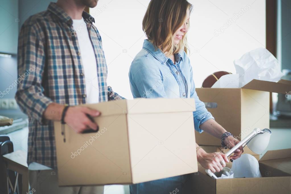 Couple unpacking cardboard boxes in their new home. Young couple.