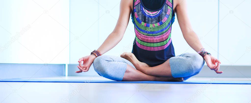 Young woman doing yoga at home in the lotus position