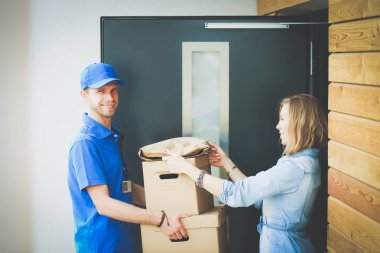Mavi üniformalı gülümseyen kurye servis konseptine paket kutusu teslim eden teslimatçı. Mavi üniformalı gülümseyen teslimatçı.