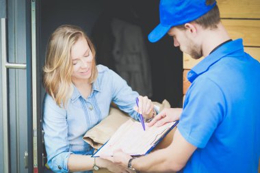 Mavi üniformalı gülümseyen kurye servis konseptine paket kutusu teslim eden teslimatçı. Mavi üniformalı gülümseyen teslimatçı.