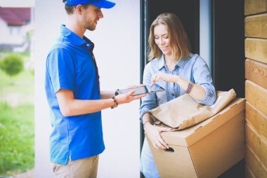 Mavi üniformalı gülümseyen kurye servis konseptine paket kutusu teslim eden teslimatçı. Mavi üniformalı gülümseyen teslimatçı.