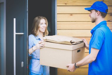 Mavi üniformalı gülümseyen kurye servis konseptine paket kutusu teslim eden teslimatçı. Mavi üniformalı gülümseyen teslimatçı.