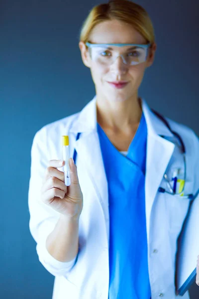Ženská lékařka nebo výzkumná vědkyně nebo lékařka, která se dívá na zkumavku s čirým roztokem v laboratoři nebo laboratoři. — Stock fotografie