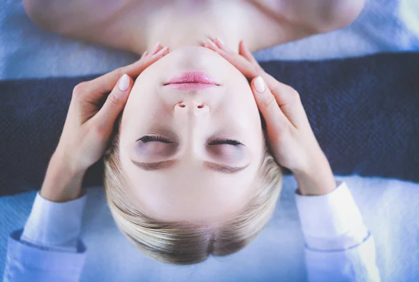 Młoda kobieta leżąca na stole do masażu, relaksująca się z zamkniętymi oczami. Kobietę. Salon spa — Zdjęcie stockowe