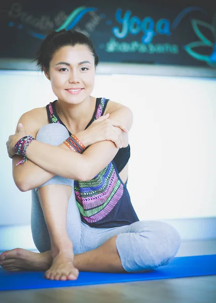 Retrato de una mujer sonriente de yoga sentada en la esterilla de yoga después del entrenamiento en el estudio de yoga. Yoga. Mujer. . — Foto de Stock