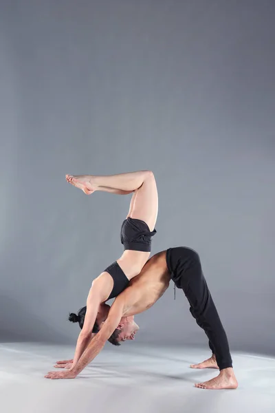 Young couple practicing acro yoga on mat in studio together. Acroyoga. Couple yoga. Partner yoga. — Stock Photo, Image