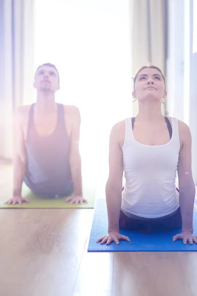 Joven pareja sana en posición de yoga sobre fondo blanco — Foto de Stock