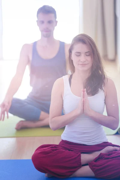Joven pareja sana en posición de yoga sobre fondo blanco —  Fotos de Stock