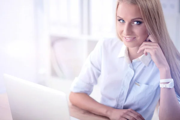 Aantrekkelijke zakenvrouw zit op een bureau met laptop in het kantoor — Stockfoto