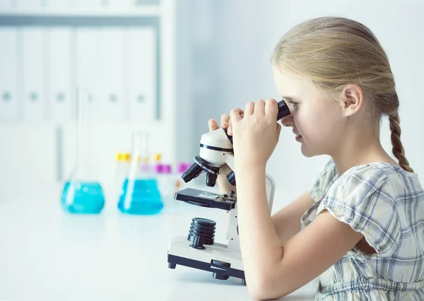 Colegiala mirando a través del microscopio en la clase de ciencias — Foto de Stock