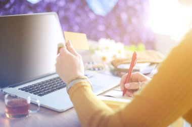 Kredi kartı tutan ve dizüstü bilgisayar kullanan genç bir kadın. Çevrimiçi alışveriş kavramı