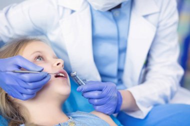 Küçük kız dişçi ofisinde oturuyor.